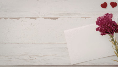 A beautiful pink flower with a white card on a wooden background with two small red hearts