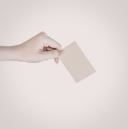 A hand holding a small piece of paper against a white backgroundの写真素材