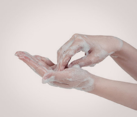 A close-up of two hands covered in soap, demonstrating the act of handwashing.