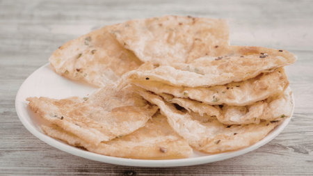 A plate of flatbread with herbs on a wooden table
