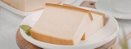 A slice of cheesecake on a white plate with a brown crust and creamy filling