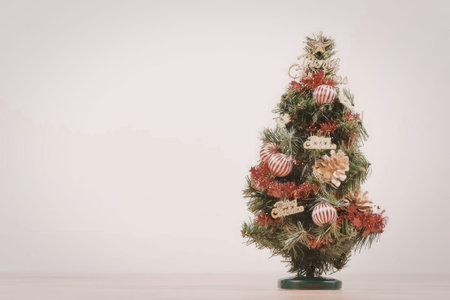 A small Christmas tree decorated with red and gold ornaments on a white background