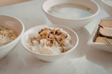 A bowl of rice topped with ingredients, accompanied by a bowl of soup and another dish with crackers...
