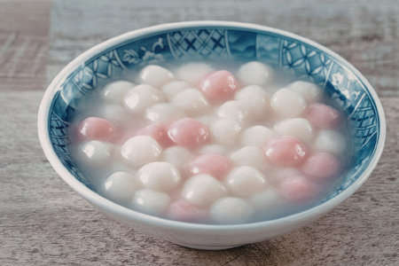 A bowl of colorful glutinous rice balls in a sweet broth, typically served as a dessert in Chinese...
