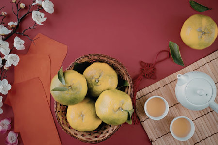 A festive setup for Chinese New Year with oranges, tea, and decorations on a red background