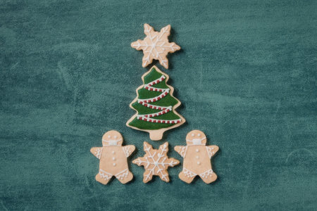 A Christmas tree and star shaped cookies with gingerbread men on a green background