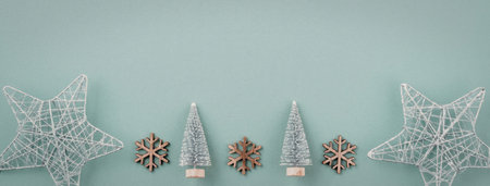 A festive arrangement of Christmas decorations on a light blue background, featuring star ornaments,...