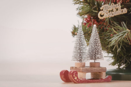 A festive Christmas decoration featuring two small silver trees on a wooden base, surrounded by a...