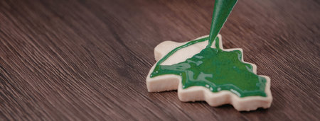 a christmas tree shaped cookie being decorated with green icing on a wooden surface