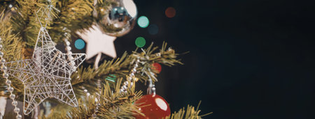 A close-up of a Christmas tree with ornaments and lights on a dark background.の写真素材