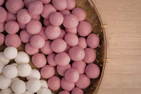 A bowl filled with pink and white candy balls on a wooden surface