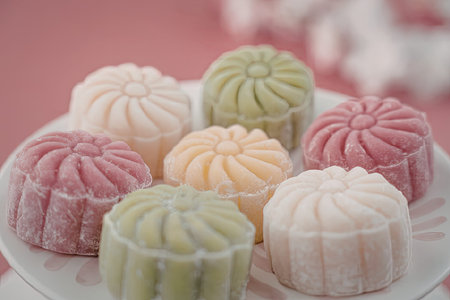 A plate of colorful mochi desserts in various flavors and colors, including pink, green, yellow, and...