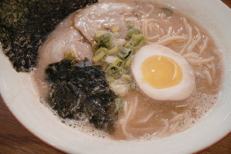 A steaming bowl of ramen noodle soup with egg, seaweed, and green onions