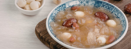 A bowl of soup with various ingredients, including red dates, quail eggs, and possibly meat or tofu,...