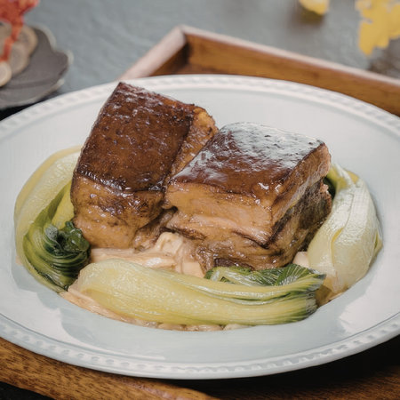 A mouth-watering dish of braised pork belly served with steamed bok choy on a white plate.