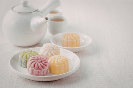 A plate of assorted mooncakes with a teapot and cup in the background
