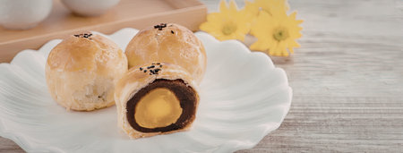 A plate of pastries with one cut open to reveal a dark brown and orange filling, on a wooden table...