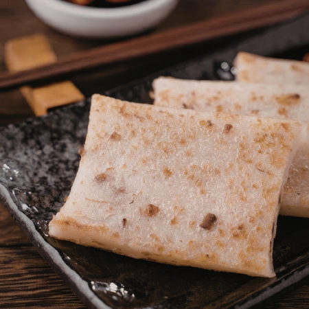 A close-up view of square shaped food on a black plate, possibly a type of pancake or flatbread,...