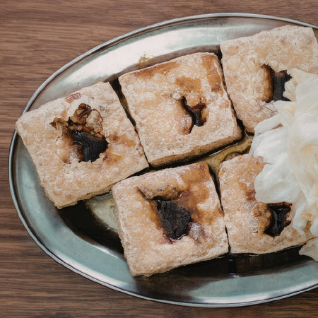 A plate of square shaped desserts with a dark center, possibly a type of cake or pastry, served on a...