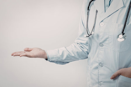 A doctor wearing a white coat and stethoscope gestures with their handの写真素材