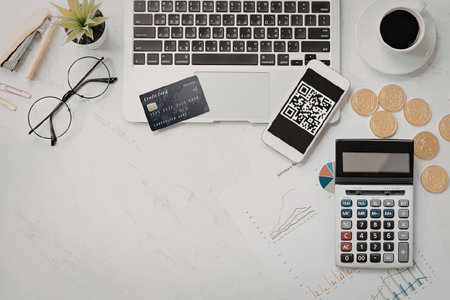 A workspace setup for financial planning with a laptop, smartphone, credit card, calculator, coins,...