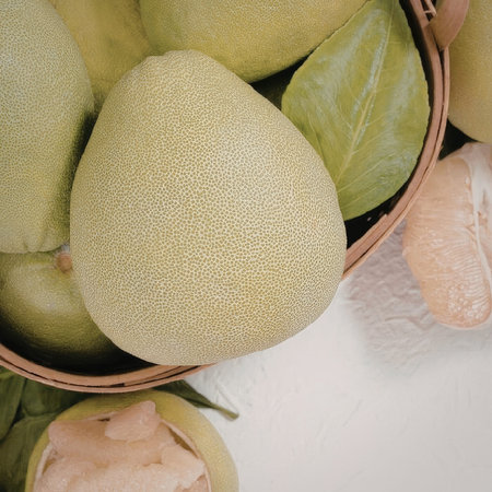 A close-up of green pears in a basket with a halved pear and green leaves
