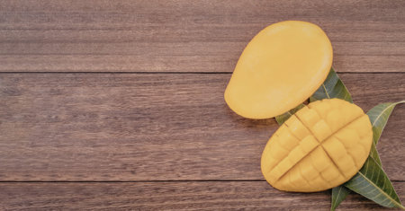 A sliced mango with a green leaf on a wooden table