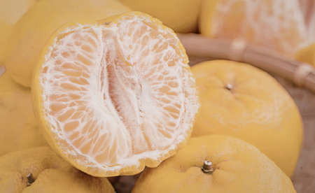 A close-up view of vibrant orange satsumas, one peeled to reveal its segments, surrounded by whole...