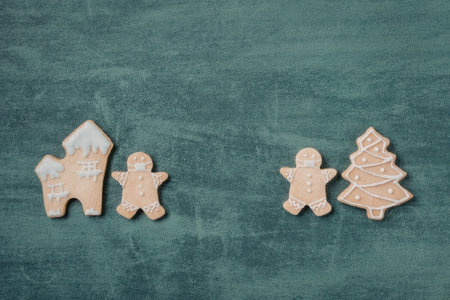A set of gingerbread cookies in the shape of a house, a man, and a Christmas tree, arranged on a...