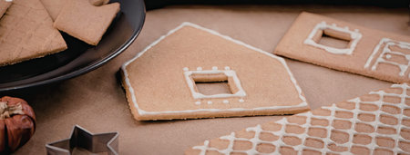A festive scene featuring gingerbread house pieces, icing, and decorations.