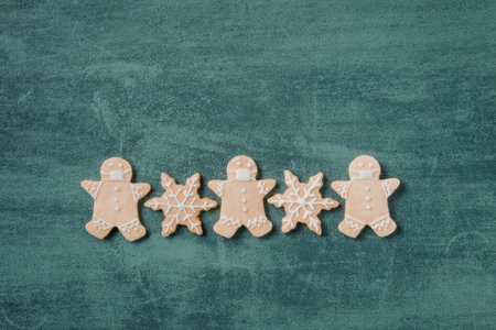 A row of four gingerbread cookies on a green surface