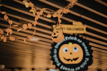A close-up of a Halloween decoration featuring a pumpkin and orange leaves hanging in front of a...