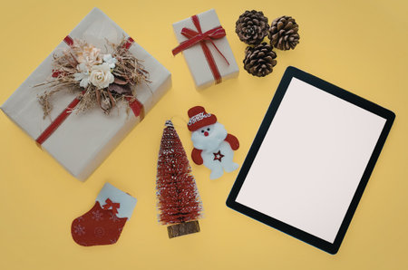 A collection of Christmas objects including gifts, tree, stocking, snowman, and tablet on a bright...