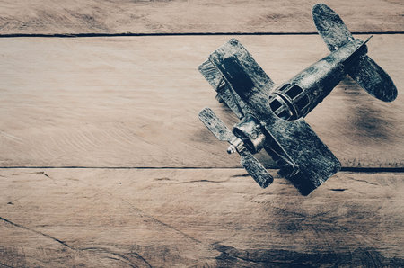 A small, vintage metal airplane model sits on a wooden surface, showcasing its detailed design and...