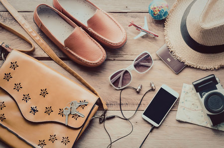 A collection of summer vacation essentials including a smartphone, sunglasses, sandals, and a hat...