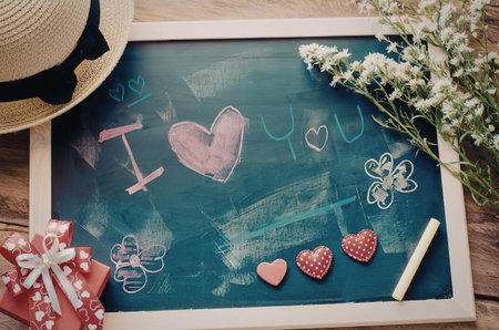 A chalkboard with a heartfelt message 'I love you' written in chalk, surrounded by flowers, a straw...