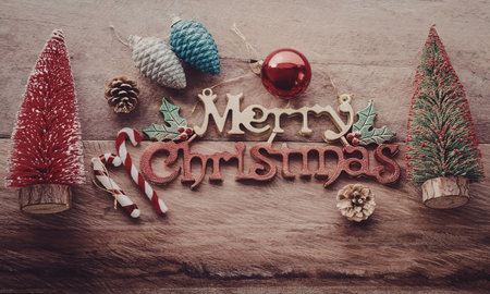 A festive Christmas scene with miniature trees, ornaments, and a candy cane on a wooden background...
