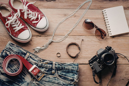 A collection of fashion accessories and photography equipment on a wooden surface