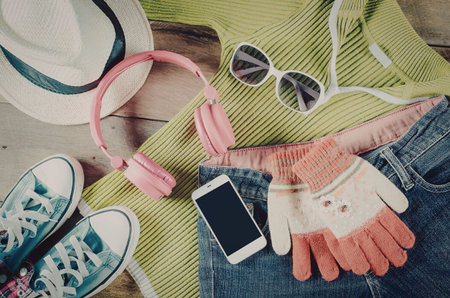 A collection of summer fashion accessories including a green sweater, headphones, sunglasses,...