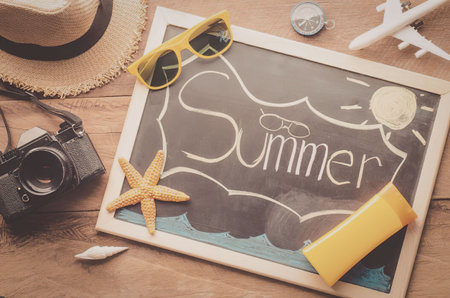 A chalkboard with summer written on it surrounded by summer vacation itemsの写真素材