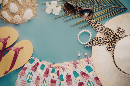 A colorful arrangement of summer vacation essentials including a straw hat, sunglasses, flip flops, seashells, and beachwear.の写真素材