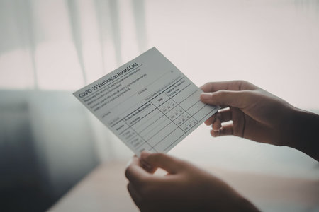 A person is holding a medical form in their hands, with a blurred background that appears to be an...
