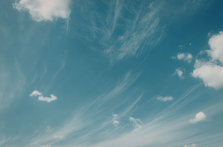 A serene blue sky with wispy white clouds scattered across it.