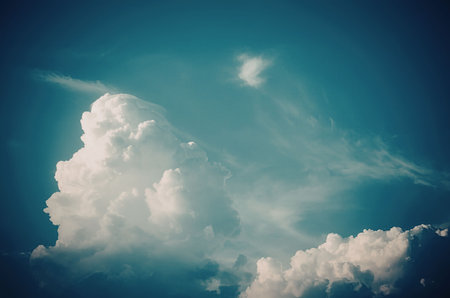 A large white cloud is in a blue sky with some smaller cloudsの写真素材
