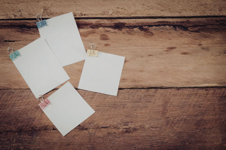 Four blank white notes with colorful push pins on a wooden background