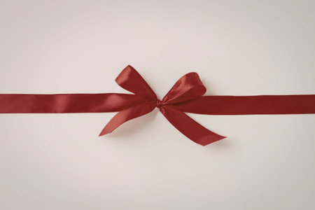 An image of a red ribbon with a bow on a beige background.の写真素材