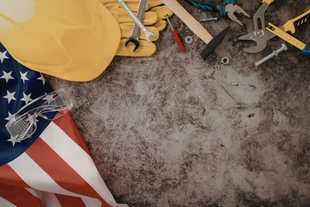 A collection of construction tools and safety gear on a gray surface with an American flag