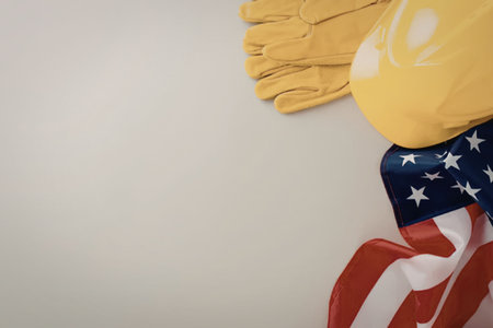 A yellow hard hat and gloves on an American flag background