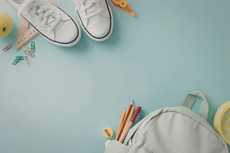 A collection of school supplies including a backpack, shoes, pencils, and an apple on a blue background.の写真素材