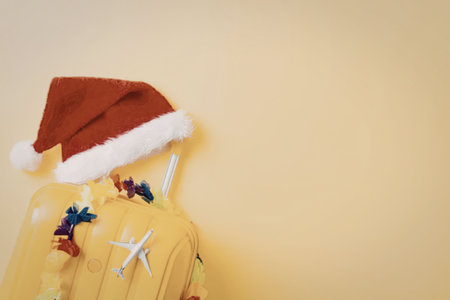 a yellow suitcase with a santa hat on top and colorful leis around itの写真素材